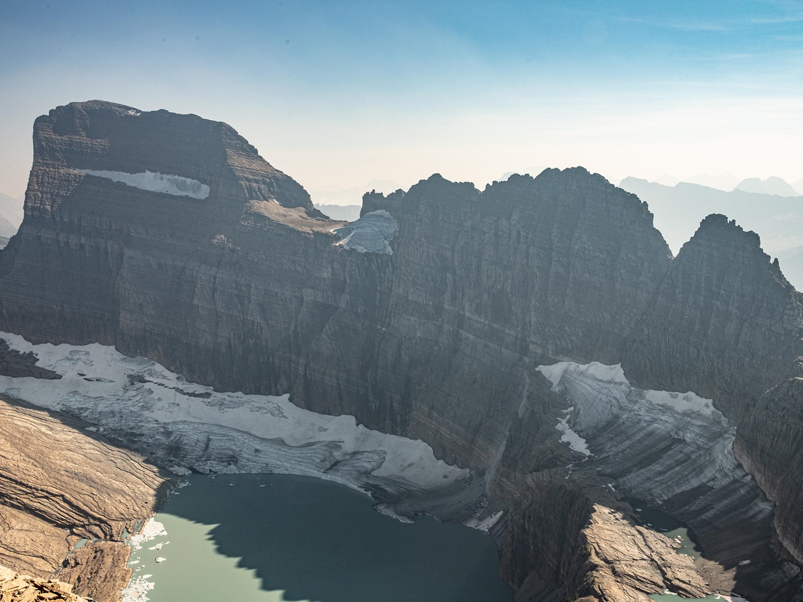 Sunlit mountain ridges, glacial ice, and a lake at Grinnell Glacier in Montana